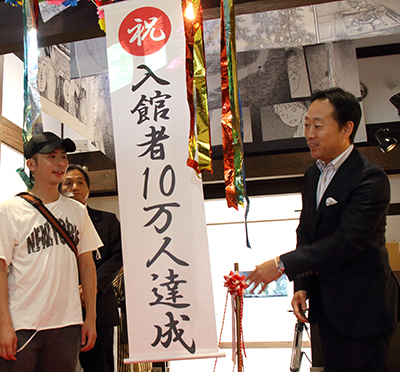10万人目の入館者とくす玉を割って達成を祝った